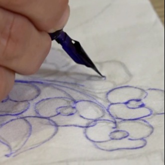 A képen egy tollal valaki éppen mintákat rajzol.