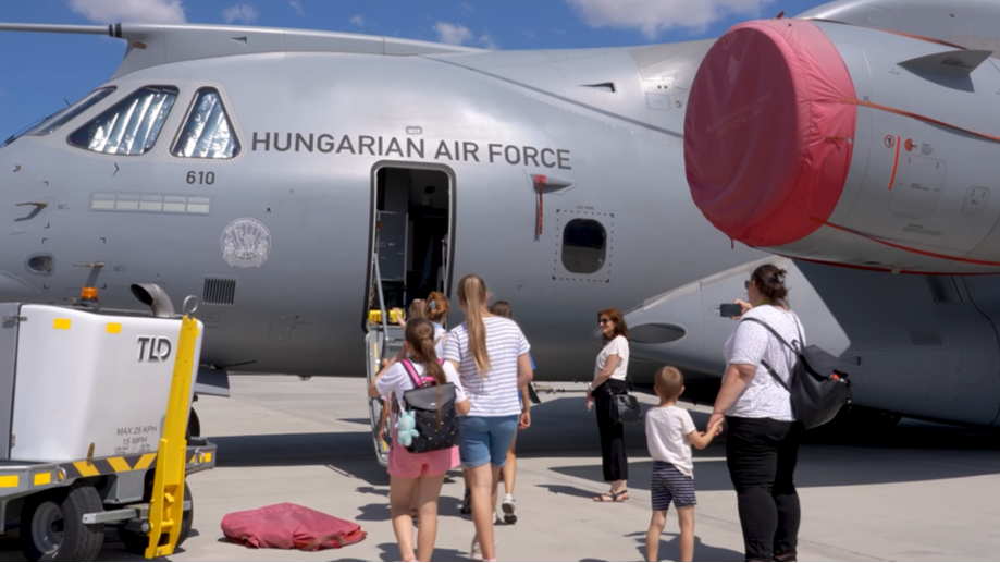 A képen egy vadászgép előtt áll egy csapat felnőtt és gyermek.