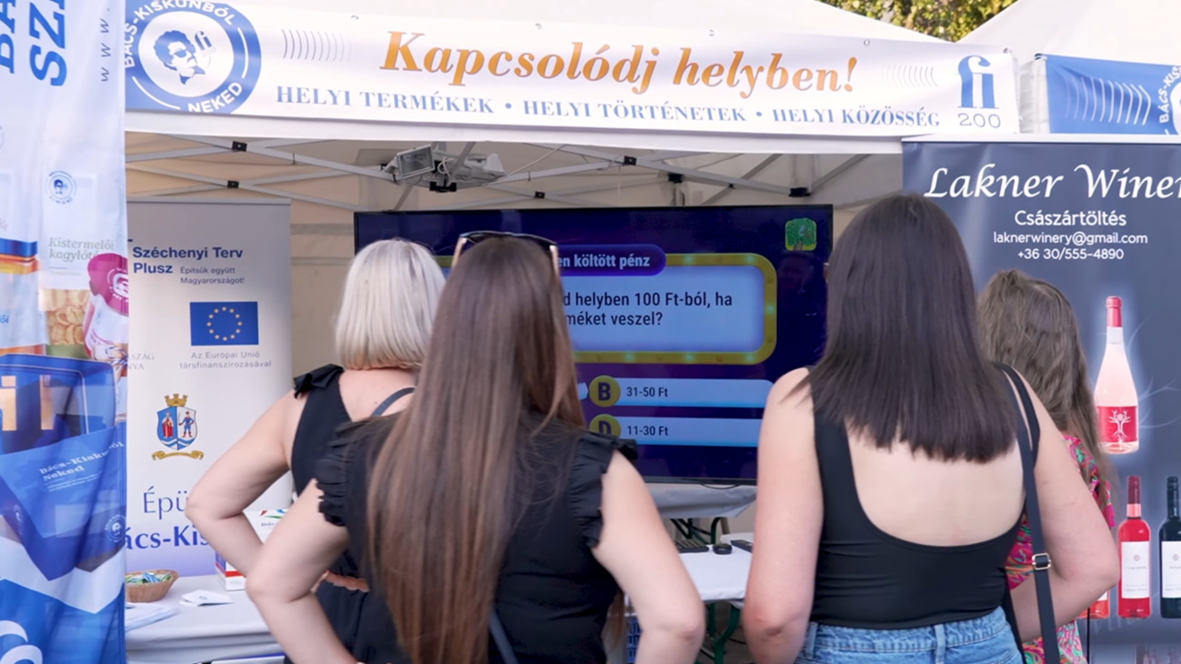 A képen a fi200 infopont standjánál hölgyek állnak.