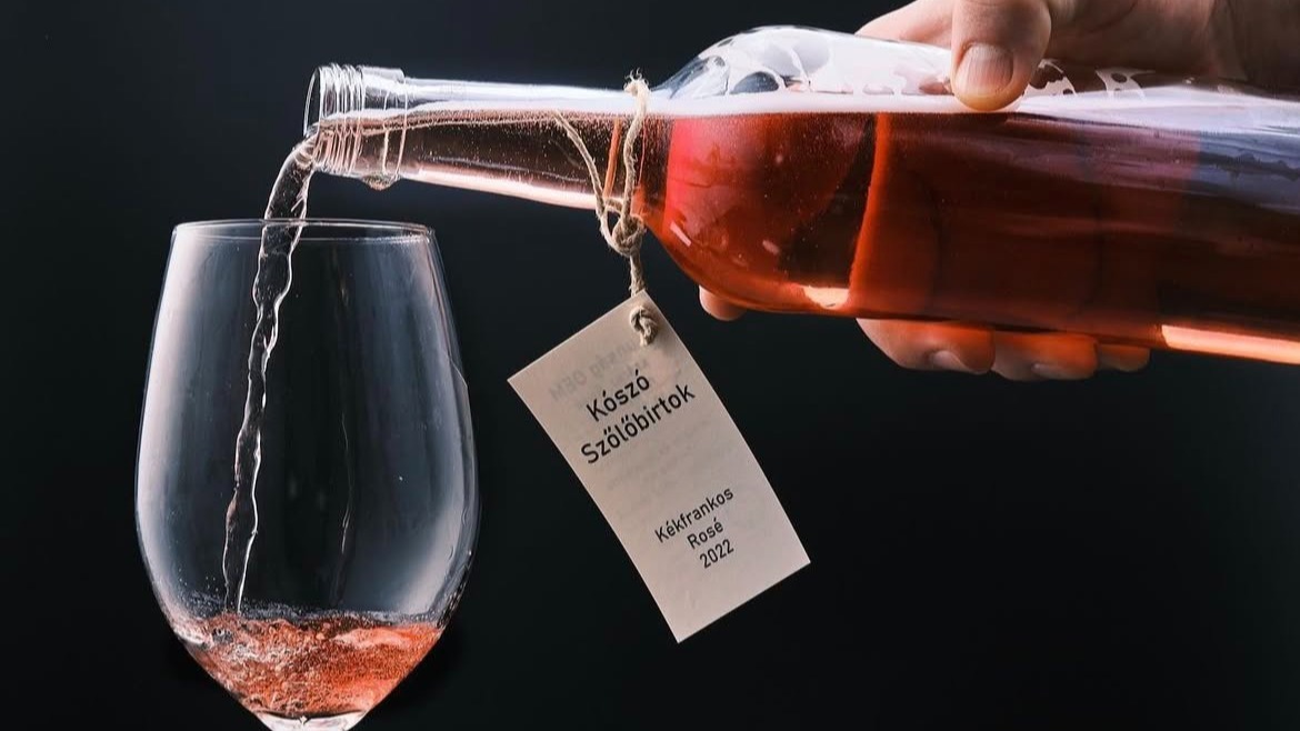 A képen egy palack Kószó Rosét töltenek ki egy borospohárba.