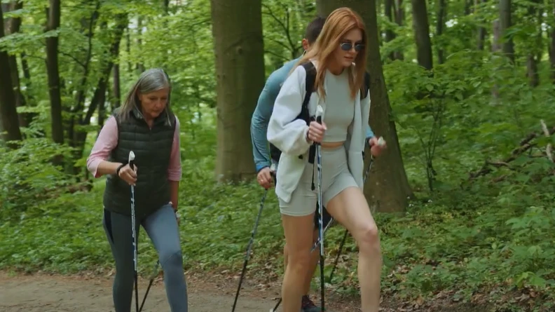 A fotón 3 nordic walkingot végző személy látható egy erdei ösvényen.