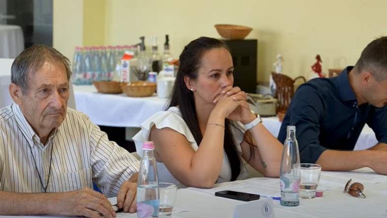 A képen a fi200 klub tagja hallgatják az előadást. Bal oldalt egy idősebb férfi, középen egy hölgy, mellette pedig egy fiatalember.