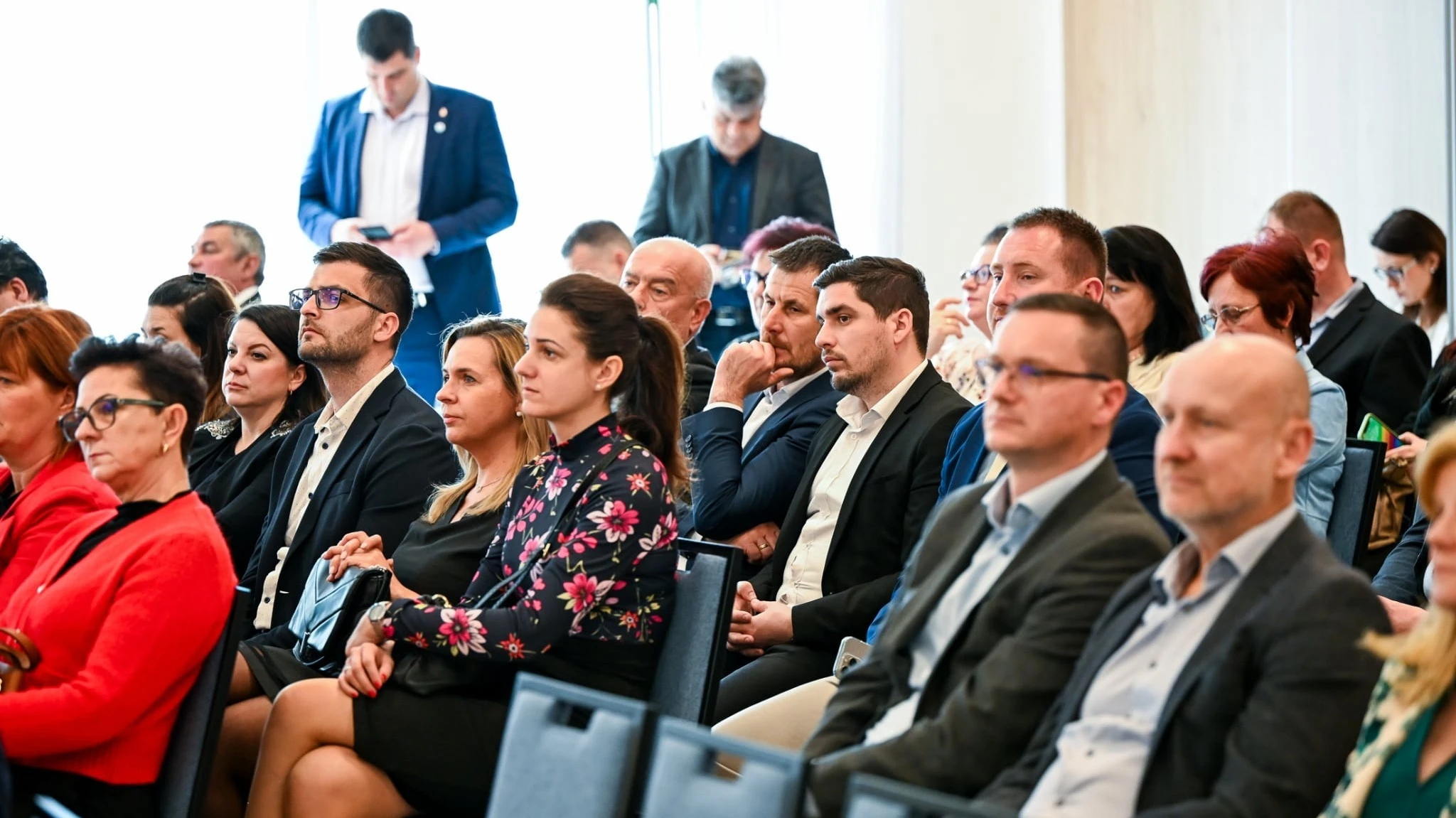 A képen több tucat ember ül egy teremben