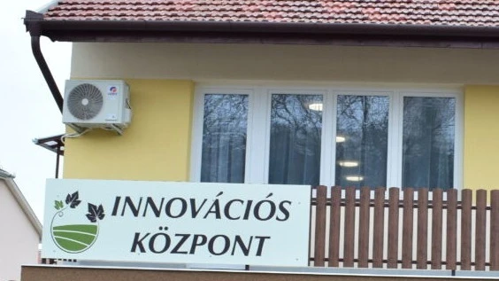 A képen egy kerítésre szerelt tábla, rajta a felirat: Innovációs Központ