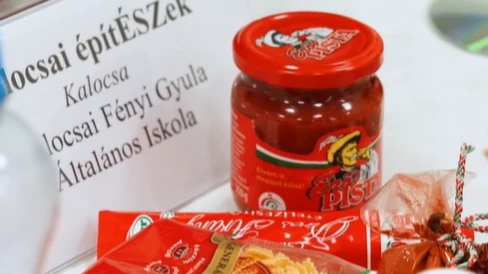 A képen egy csapat névtáblája szerepel, valamint előtte Piros Arany és Erős Pista.