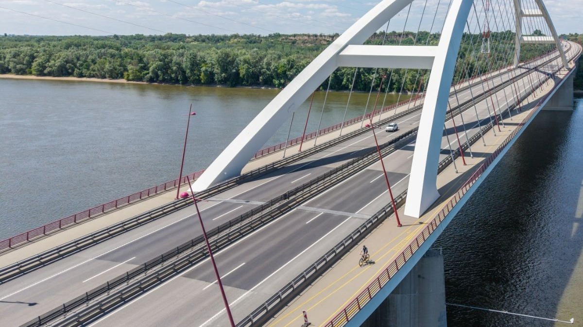 A képen egy Dunán átvezető, monumentális híd látható, rajta egy kerékpárúttal.