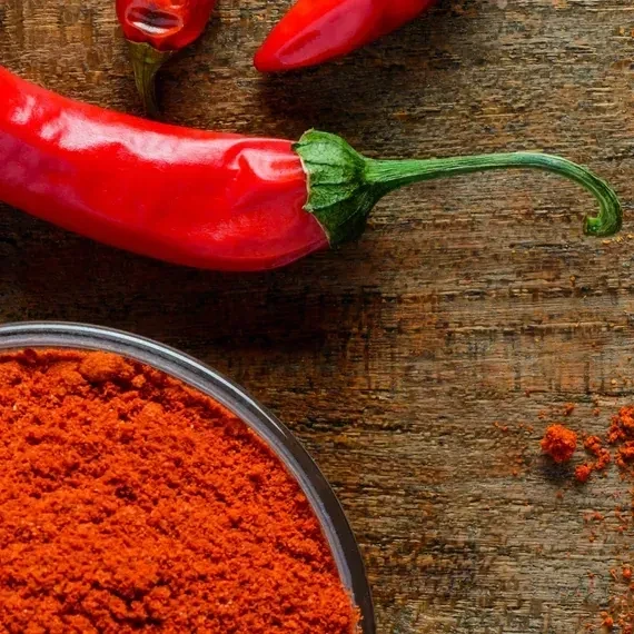 A képen fűszerpaprika őrlemény és egy egész paprika látható.