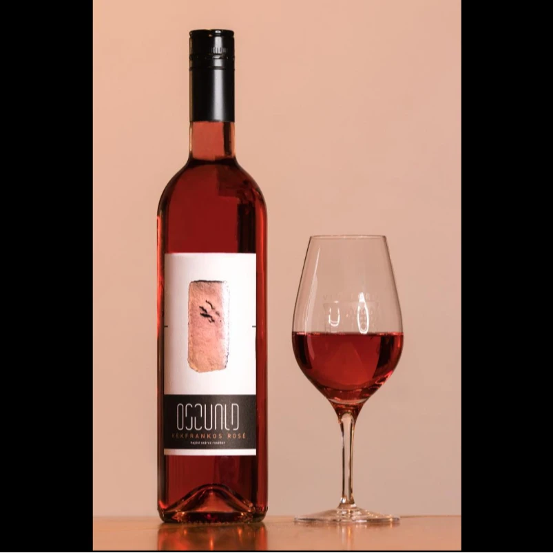 A képen az Oszvald pince kékfrankos roséja látható egy palackban, mellette pedig ugyanez egy borospohárban kitöltve.