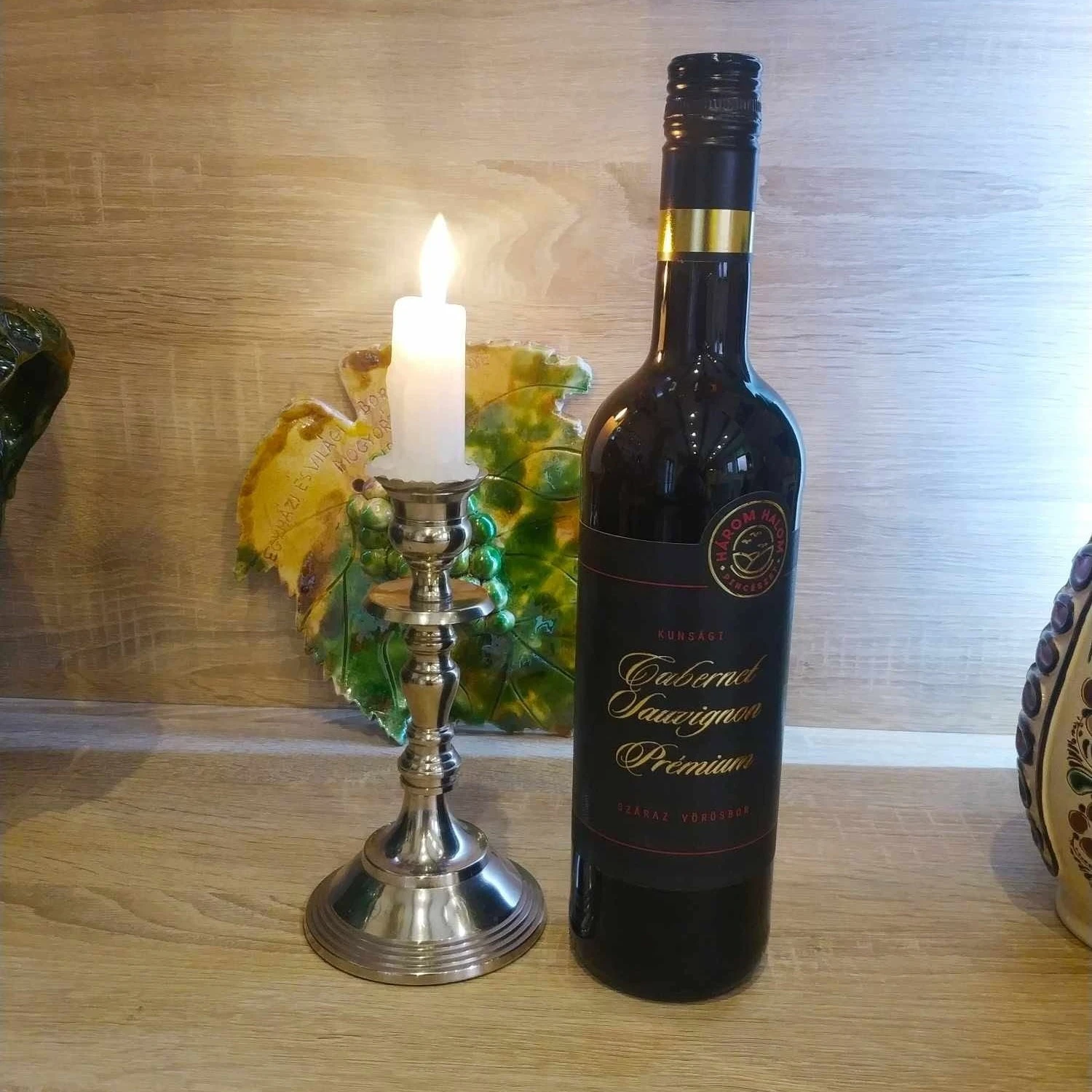 A képen egy palack Kunvin Cabernet Sauvignon Prémium látható, mellette egy gyertya.