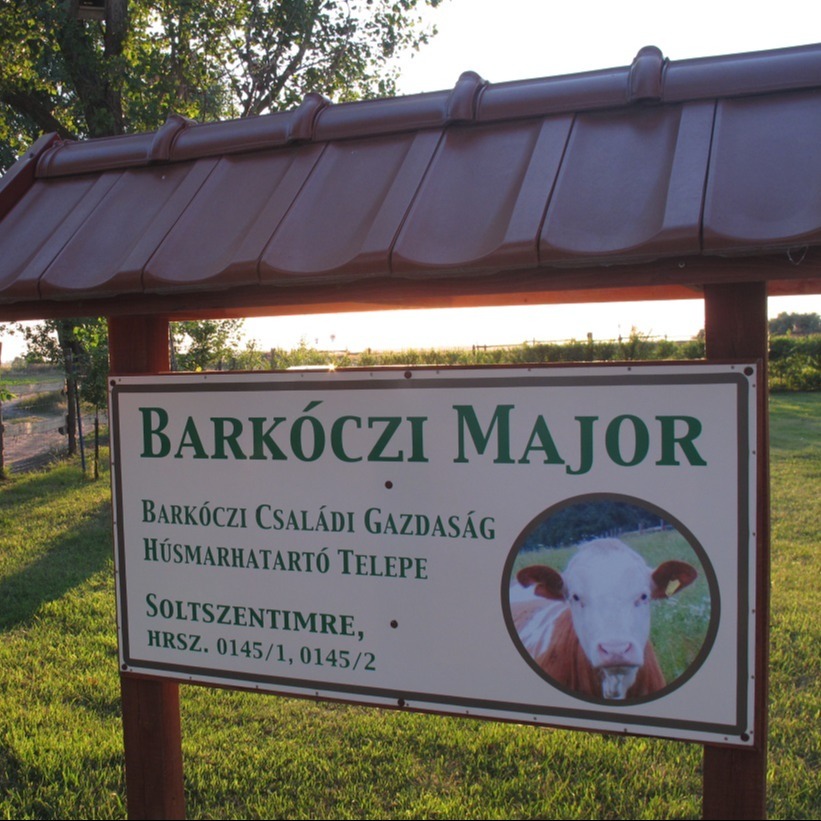 A képen egy fedett, fa szerkezetű táblán a „Barkóczi Major” felirat és a „Barkóczi Családi Gazdaság húsmarhatartó telep, Soltszentimre” szöveg látható, mellette egy tehén fényképével.
